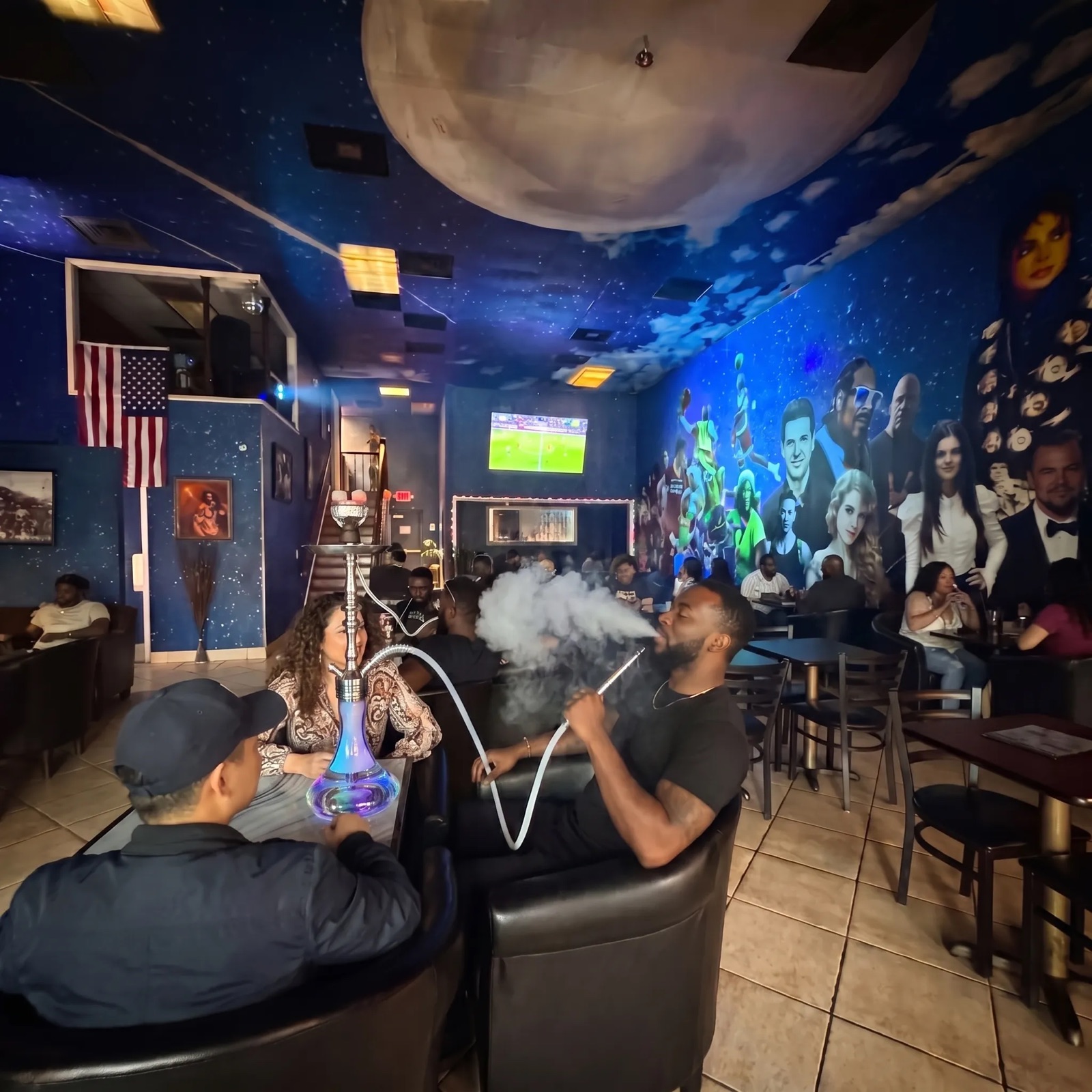 Star Light Cafe packed lounge with galaxy ceiling, celebrity mural, hookah smoke, and soccer on TV
