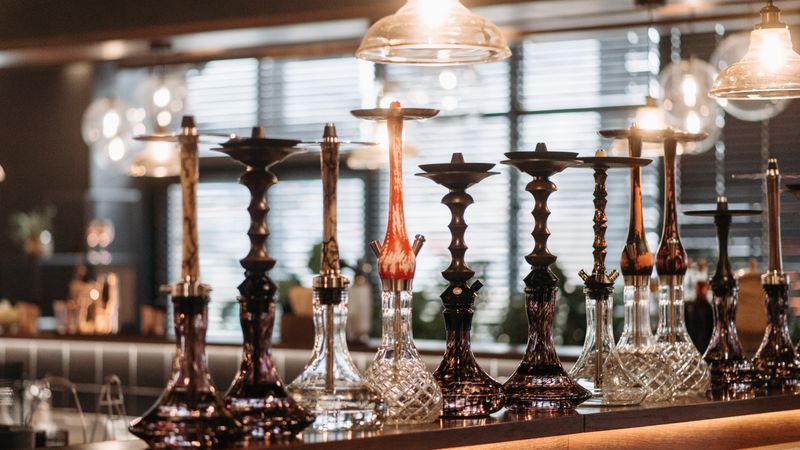 Collection of hookah pipes on a bar counter with pendant lights